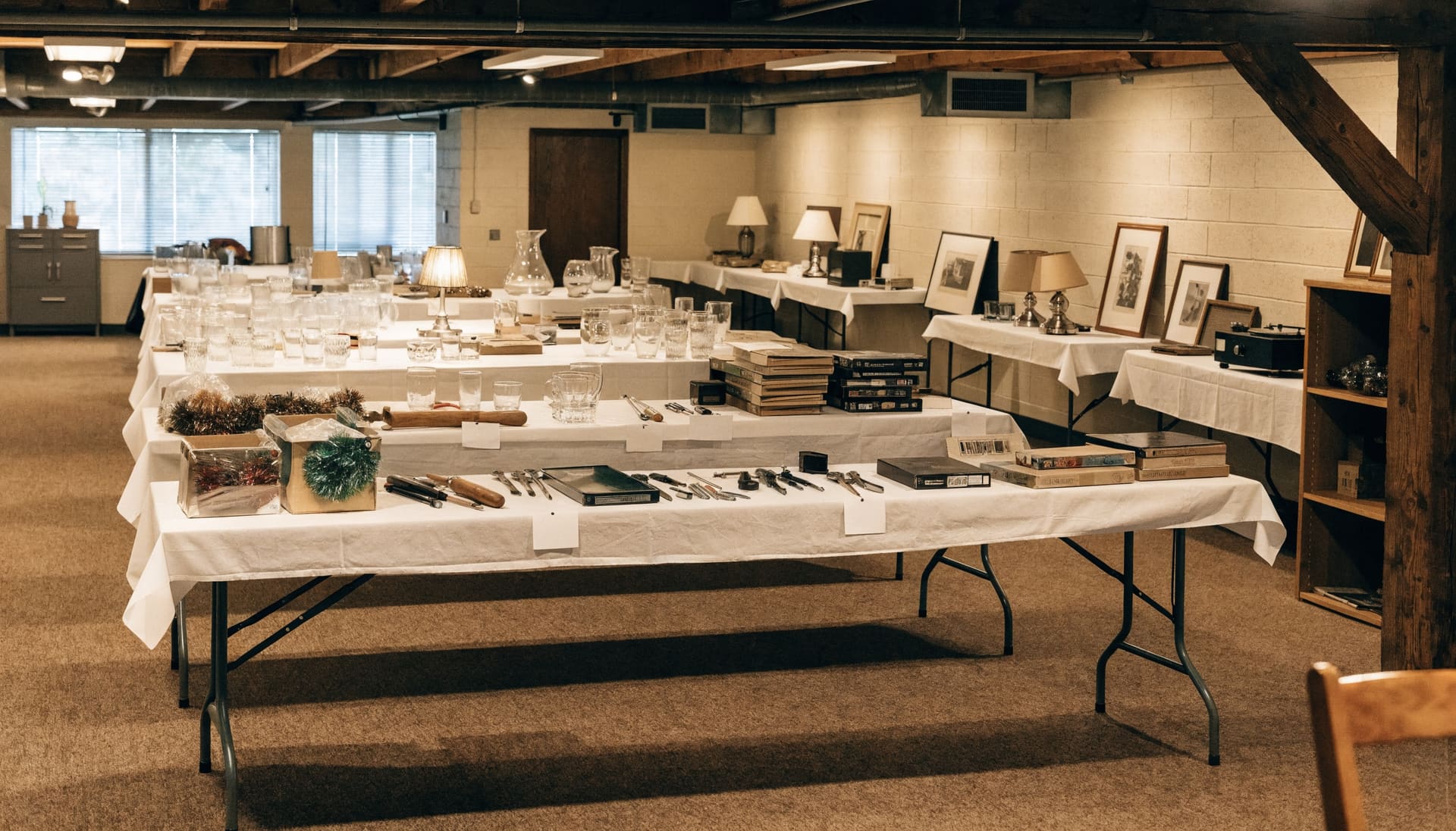 Representative image: tables of glassware, tools, books and framed prints set out for an auction preview