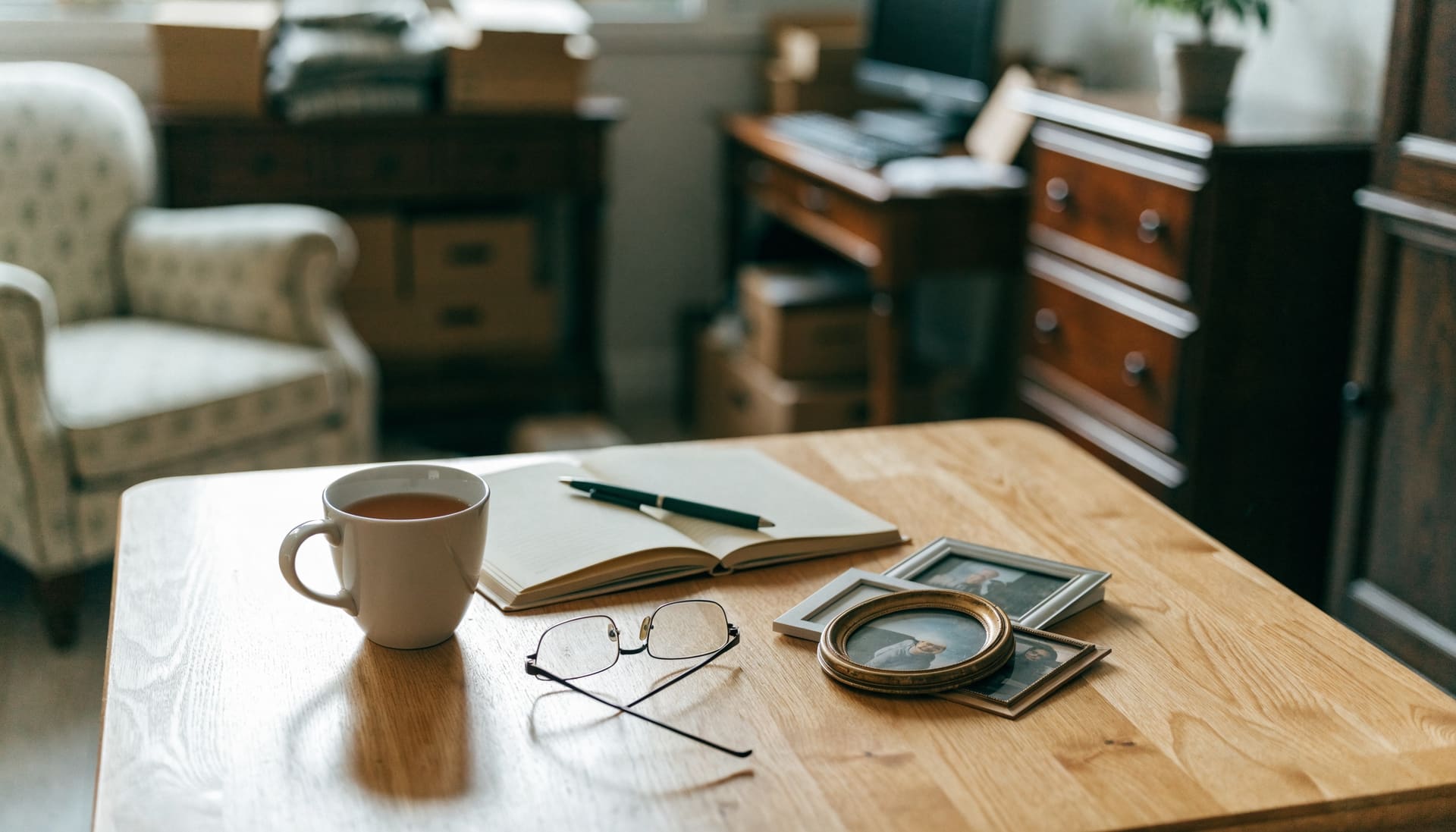 Representative image: a cup of tea, a notebook and framed family photographs on a kitchen table in a home being downsized